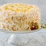 Passion fruit coconut cake decorated with toasted coconut and passion fruit curd on cake stand
