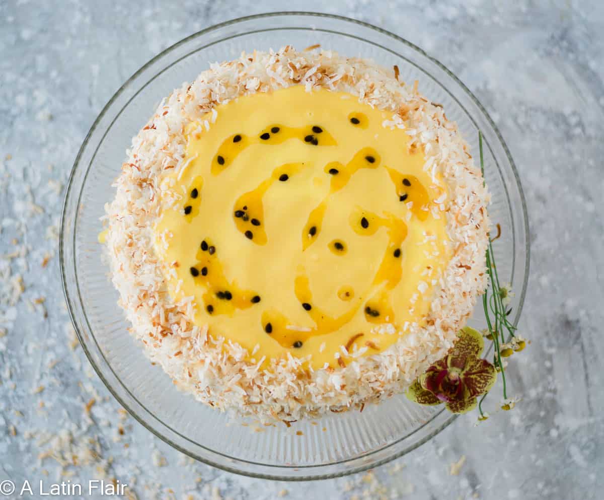 Passion fruit coconut cake decorated with toasted coconut and passion fruit curd on top overhead view