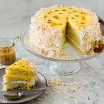 Passion fruit coconut cake on cake stand and a piece served on a gray plate