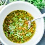 chimichurri sauce in a white bowl with parsley around