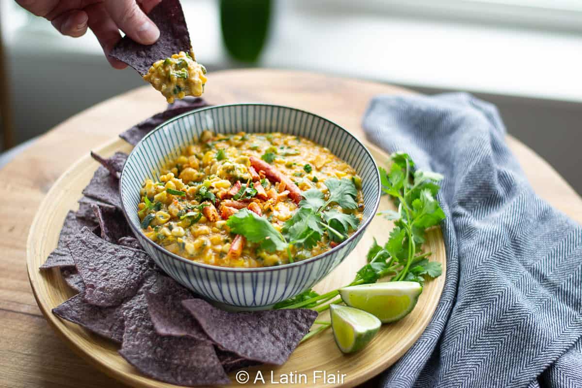 dipping-corn-chip-in-Elote-Corn-dip-with-poblano-peppers