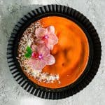 Coconut-Flan-over-black-dish-decorated-with-flowers