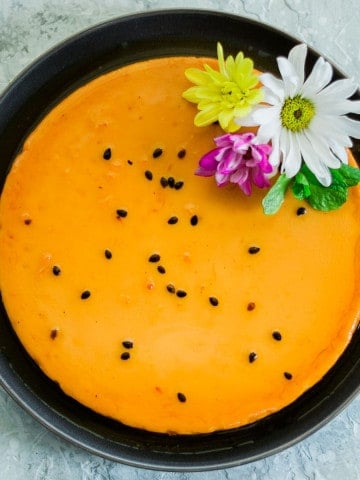 Pretty Passion Fruit Flan with flowers over a dark plate