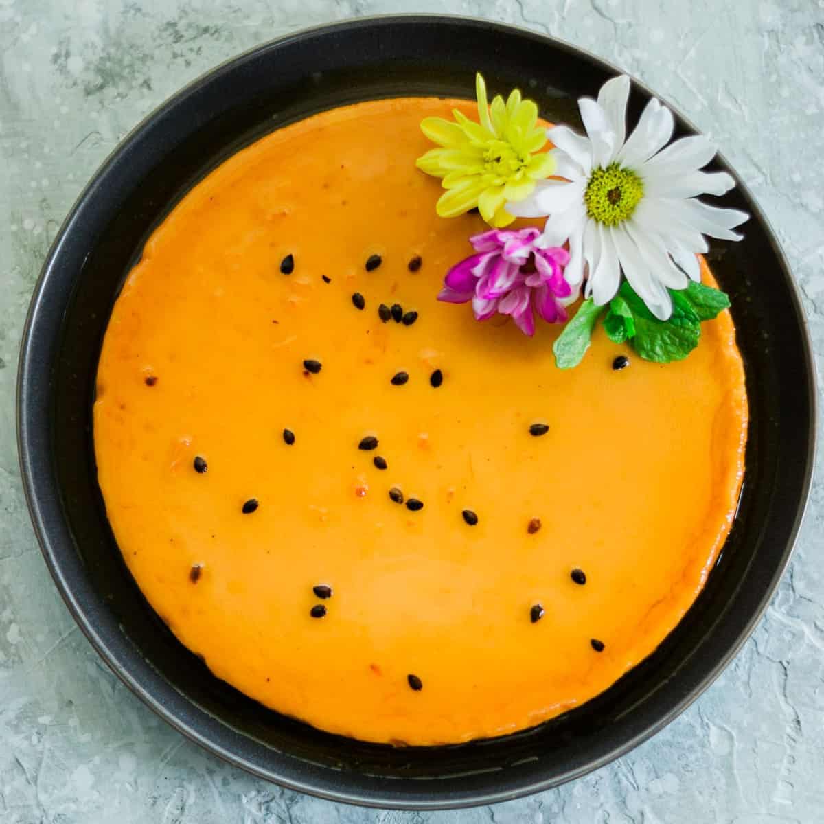 https://alatinflair.com/wp-content/uploads/2022/07/Featured-pretty-Passion-Fruit-Flan-with-flowers-over-a-dark-plate.jpg