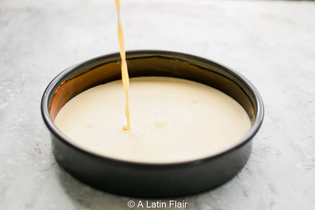 Pouring coconut flan mixture over cake pan with caramel