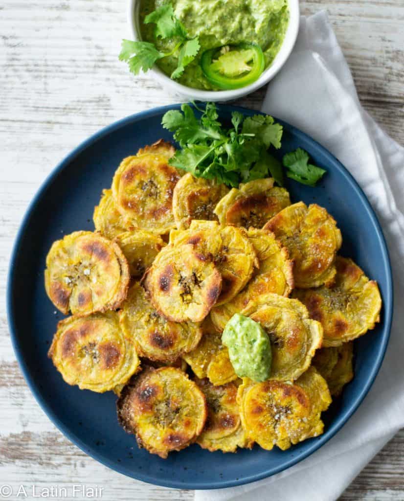 Baked-tostones-(Crispy-Baked-Green-Plantains)-on-blue-plates-with-peruvian-aji-verde-green-sauce