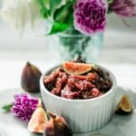 Homemade-Fig-Preserves-in-white-bowl-with-flowers-and-fresh-figs-around