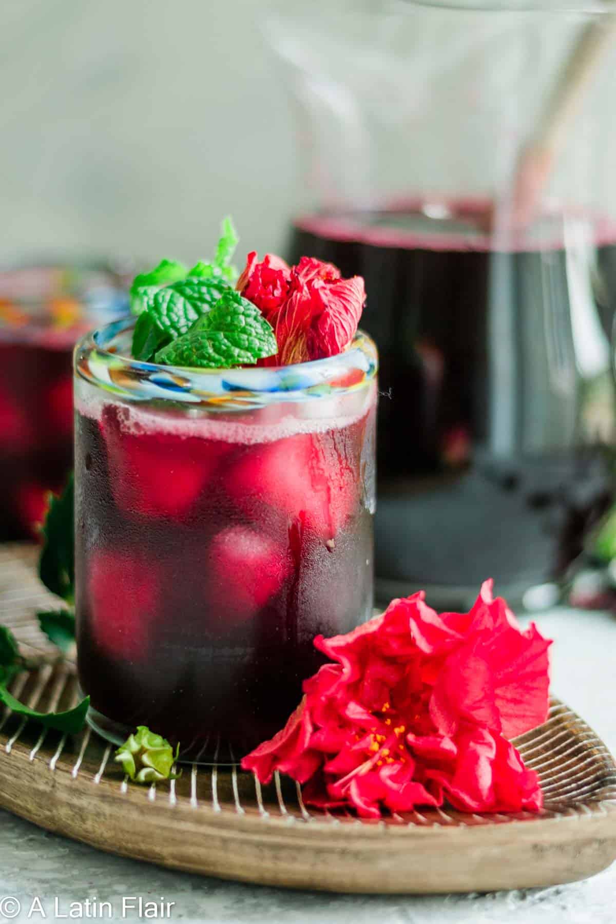 Agua- de-Jamaica-Hibiscus-Iced-Tea-in-glass-and-pitcher-in-background
