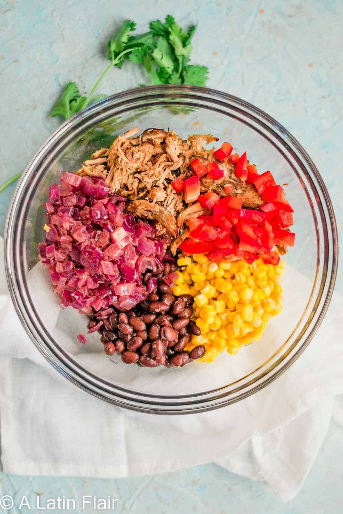 filling ingredients for quesadillas with leftover pulled Pork carnitas in a glass bowl