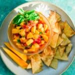 peach mango salsa on white plate and corn tortillas