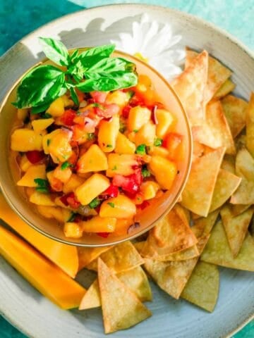 peach mango salsa on white plate and corn tortillas