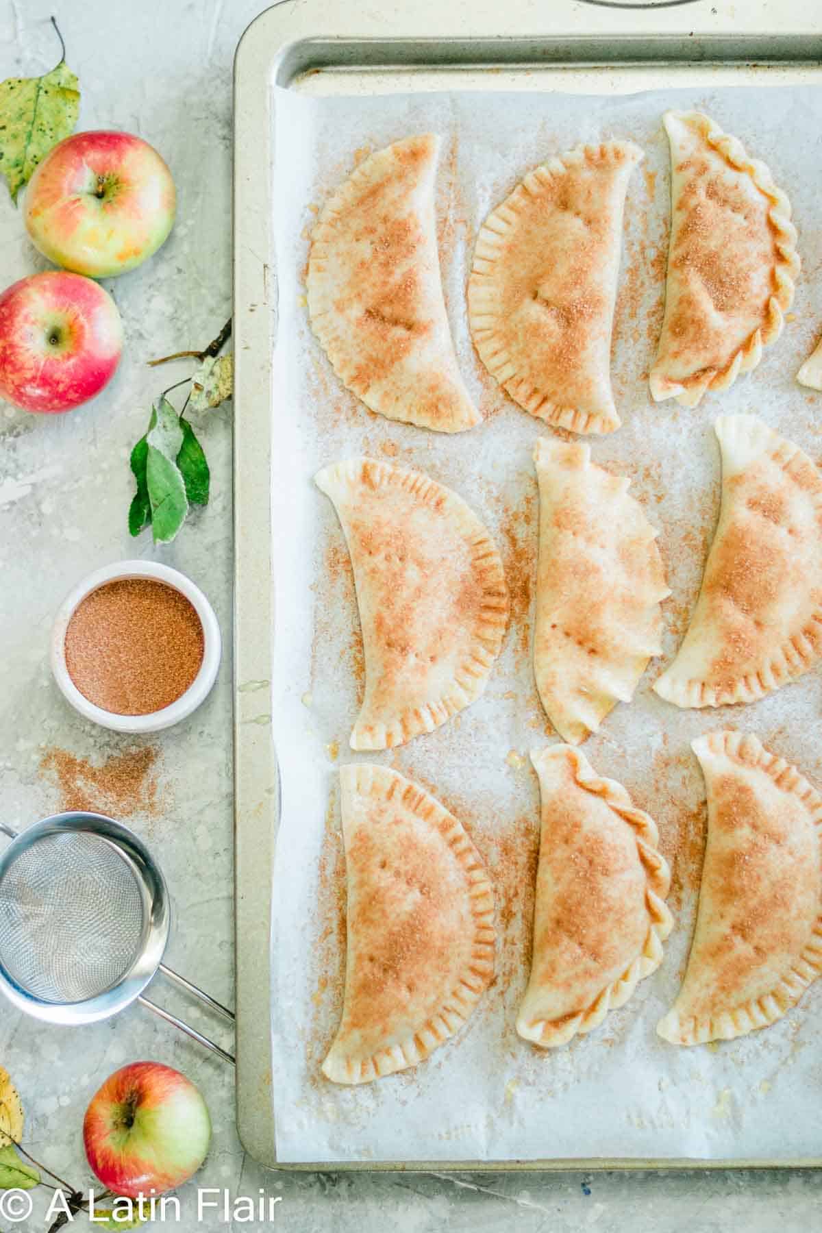 apple empanadas on baking sheet sprinkled with cinnamon sugar