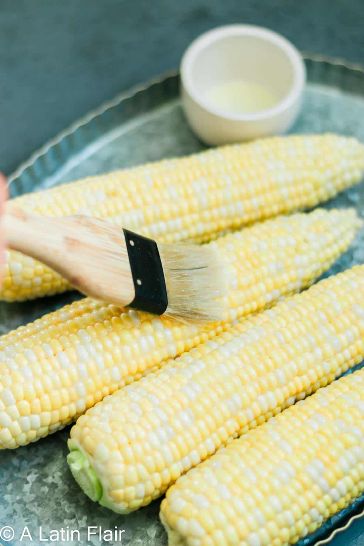 brushing butter on corn cobs for Elote Air Fryer 