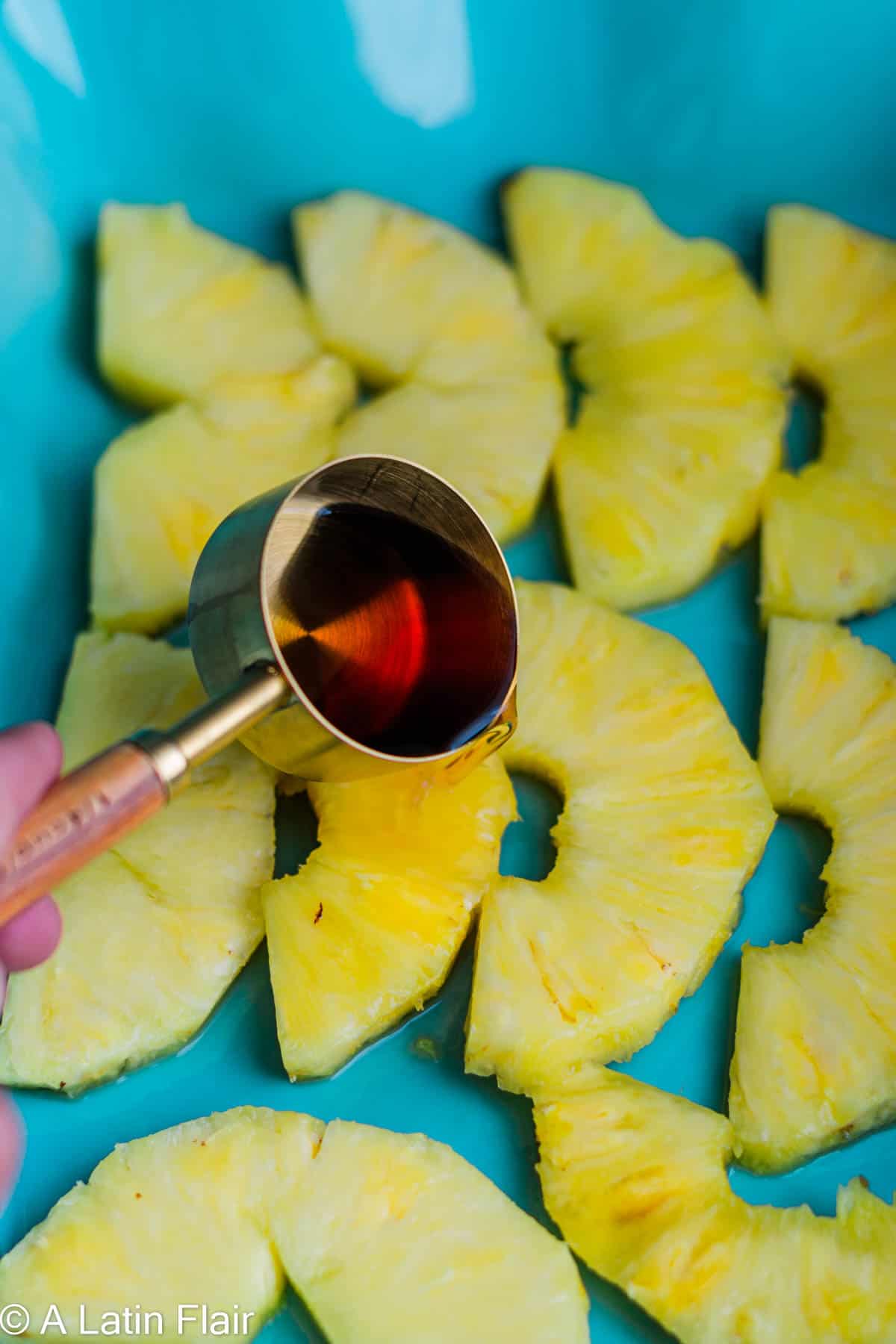 pouring rum over sliced pineapple for Upside Down Pineapple Rum Cake