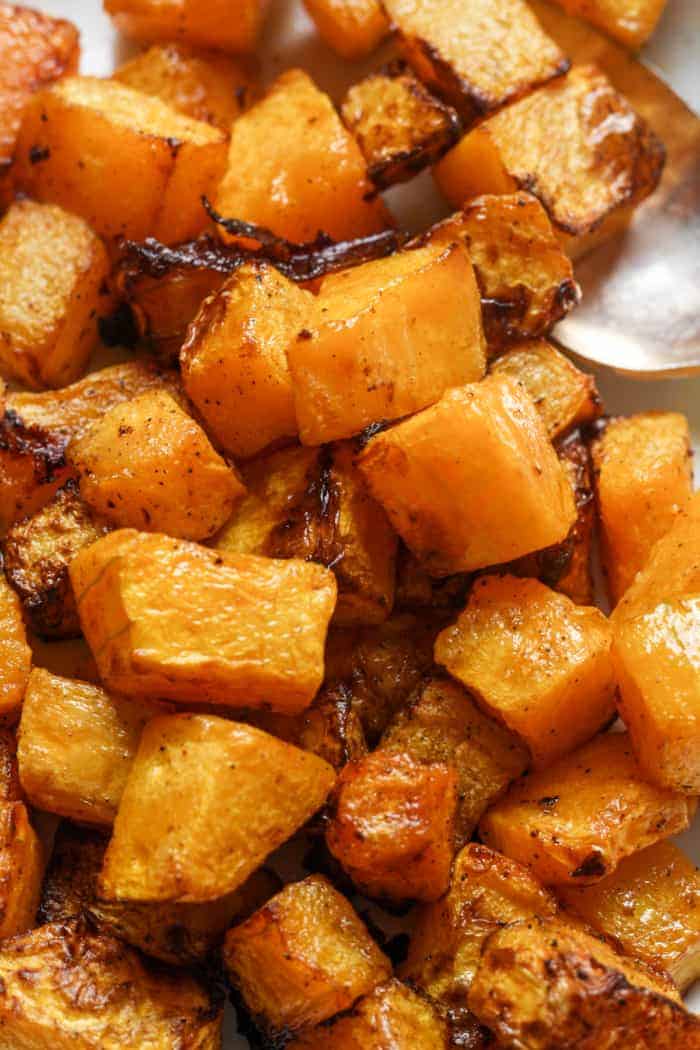 Golden roasted butternut squash cubes with caramelized edges on a baking sheet, conveying a warm and inviting autumnal tone.
