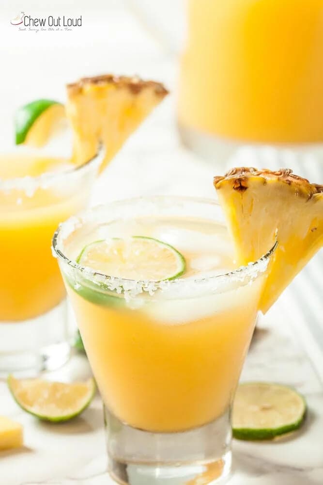 Big batch pineapple margarita recipe with salt rim, garnished with fresh pineapple wedge and lime slice, served in rocks glass.