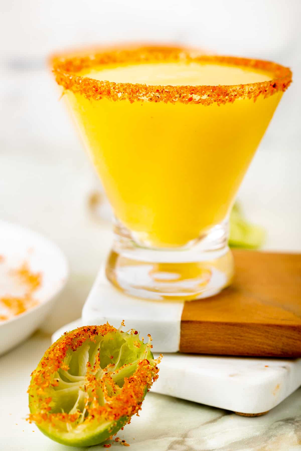 Frozen mango margarita recipe (mangorita) with Tajín chili salt rim in stemmed margarita glass with lime wheel garnish.
