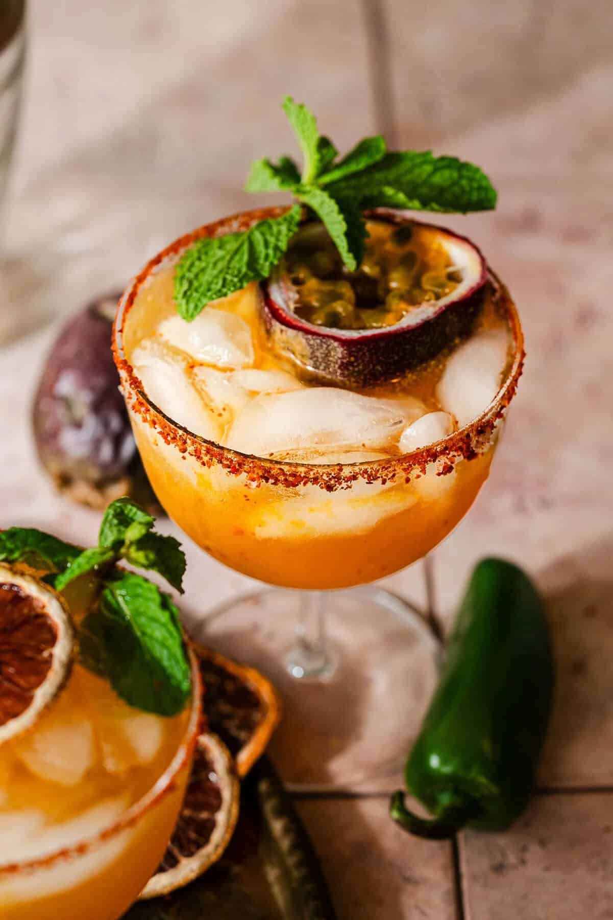 Golden passion fruit margarita recipe with chili lime salt rim, garnished with fresh passion fruit half and mint leaves.