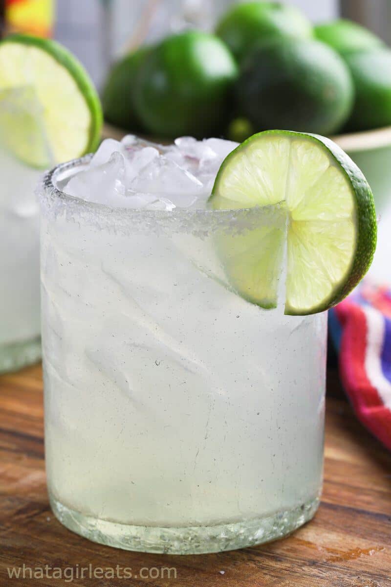 Classic 3-2-1 margarita recipe with salt rim and fresh lime garnish served over ice with whole limes in background.