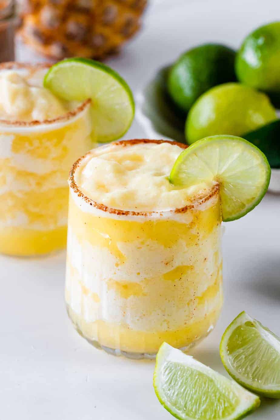 Spicy pineapple margarita recipe with chili lime salt rim and fresh lime garnish, served with jalapeños and lime wedges.