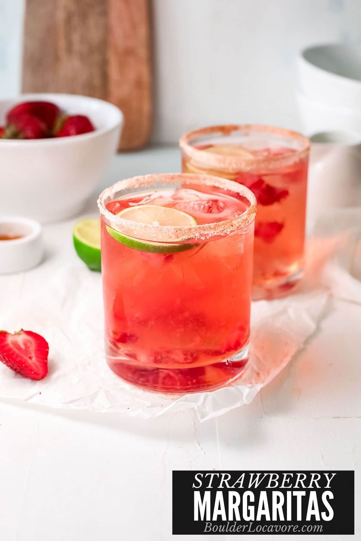 Strawberry margarita recipe with salt rim and lime garnish in rocks glasses, served with fresh strawberries.